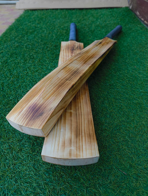 Two wooden hard tennis cricket bats on a green grass-like surface